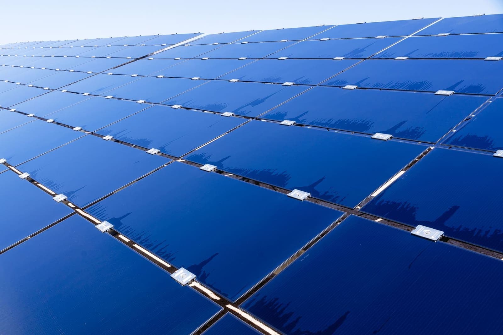 Rij zonnepanelen onder een strakblauwe hemel